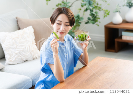 Young woman eating edamame beans lifestyle image 115944021