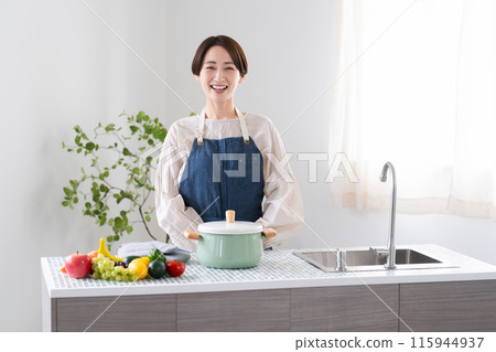 A young woman cooking in an apron Lifestyle image A young woman cooking in an apron Lifestyle image 115944937