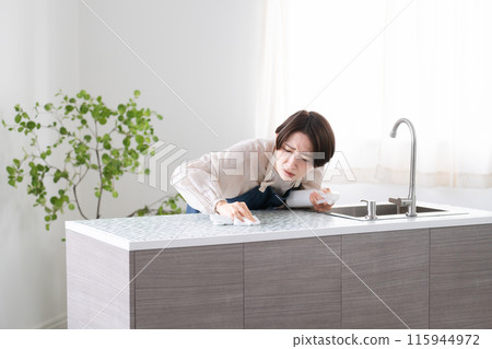 A woman in an apron cleaning the kitchen Lifestyle image A woman in an apron cleaning the kitchen Lifestyle image 115944972