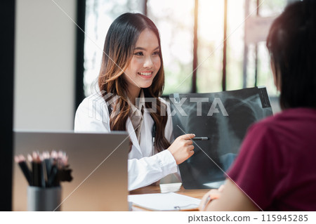 Female doctor explaining X-ray results to patient in a modern medical office. Smiling healthcare professional providing consultation and patient care. 115945285