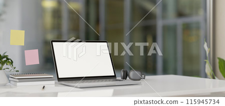 A modern office features a laptop computer with a white-screen mockup on a white desk. 115945734