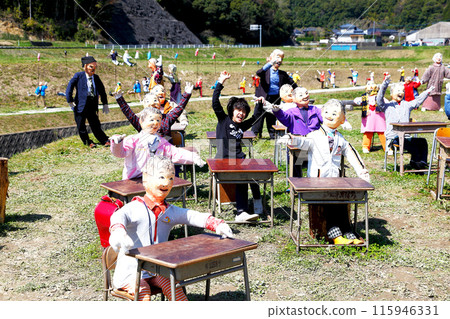 一個男孩在放著稻草人的露天教室裡舉手。 115946331