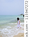 A girl wearing a dress standing on the beach 115947272