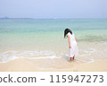 A girl wearing a dress standing on the beach 115947273