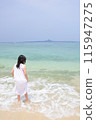A girl wearing a dress standing on the beach 115947275