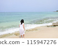 A girl wearing a dress standing on the beach 115947276