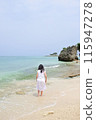 A girl wearing a dress standing on the beach 115947278
