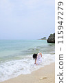 A girl wearing a dress standing on the beach 115947279