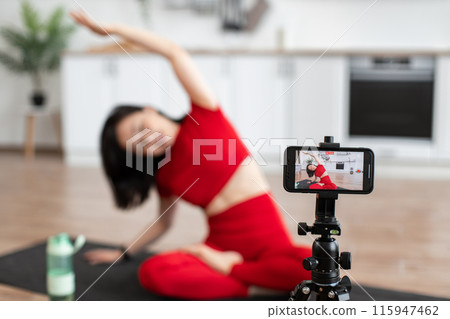Woman filming yoga session at home on smartphone Woman filming yoga session at home on smartphone 115947462