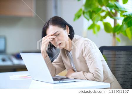 中年婦女在辦公室看起來很疲憊 中年婦女在辦公室看起來很疲憊 115951197