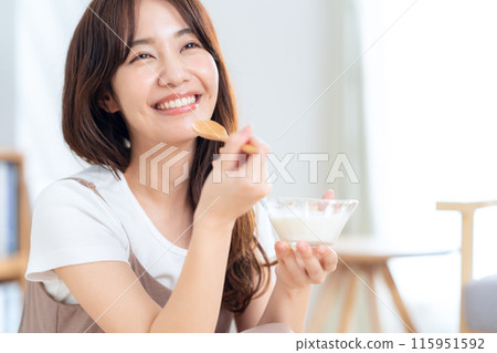Young woman eating yogurt 115951592
