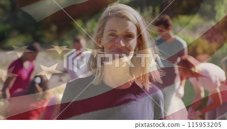 Composite image of american flag over portrait of caucasian female volunteer smiling in the forest 115953205