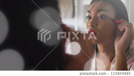 Image of light spots over biracial woman applying mascara Image of light spots over biracial woman applying mascara 115954885