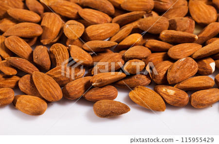 Handful of roasted almond nuts on a white surface 115955429