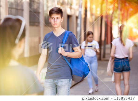 Teenager walking along city street on summer day Teenager walking along city street on summer day 115955437