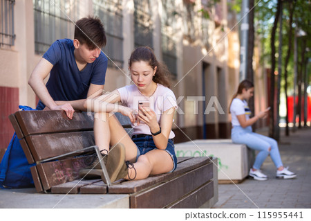 Teenage girl absorbed in phone, ignoring boyfriend Teenage girl absorbed in phone, ignoring boyfriend 115955441