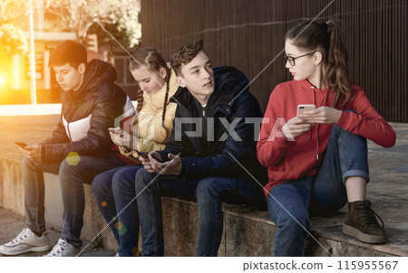Teenagers chatting on their smartphone on walking 115955567