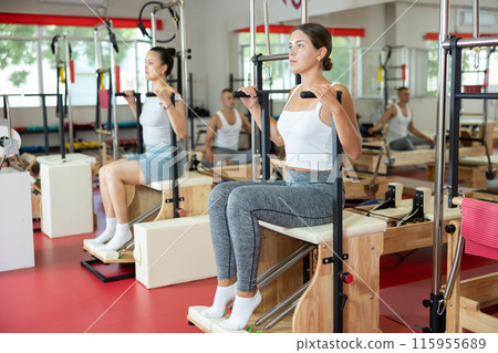 Young woman doing arm exercises on pilates machine 115955689