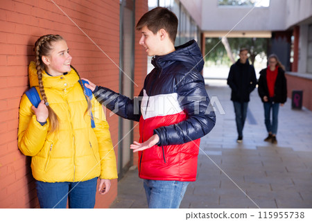 Two teenage students talking near college Two teenage students talking near college 115955738
