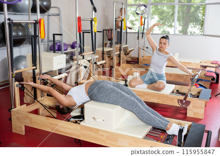 Young woman training her abs on pilates machine Young woman training her abs on pilates machine 115955847