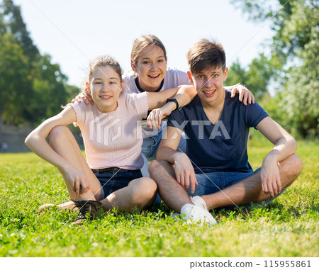 Group of teenagers chatting while sitting on green lawn 115955861