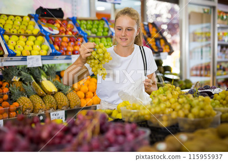 Teen shopper chooses grape at grocery store 115955937