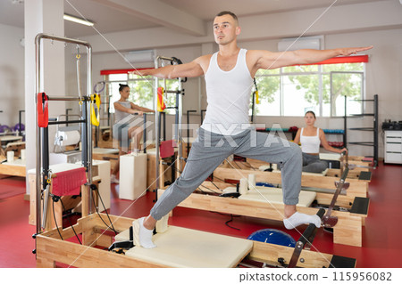 Young man doing stretching on pilates machine 115956082