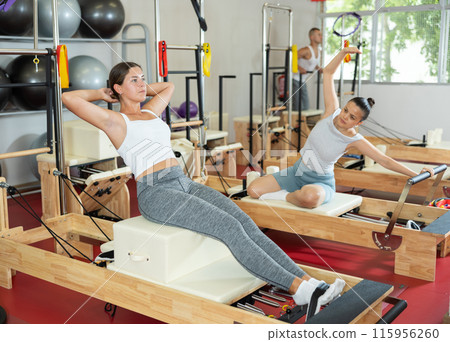 Young girl doing press exercises on reformer device 115956260