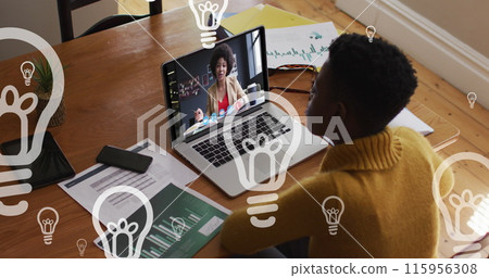 Image of floating bulbs over african american woman having image call on laptop 115956308