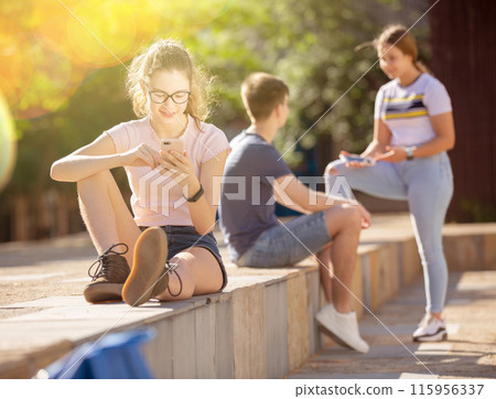 Teen girl is passionate about playing on smartphone 115956337