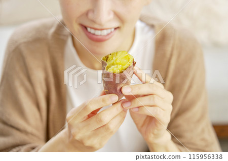 Close-up of hand holding roasted sweet potato at home 115956338