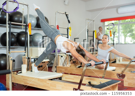 Young woman doing stretching on pilates reformer 115956353