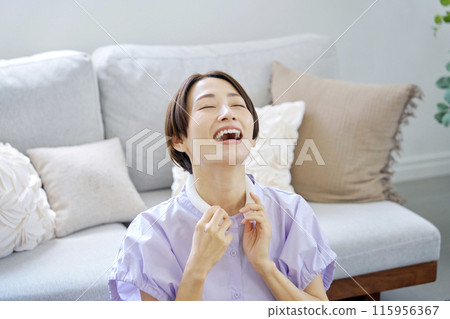 Woman using ice neck ring in living room 115956367