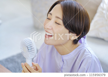 一位女士在客廳使用便攜式風扇 115956379