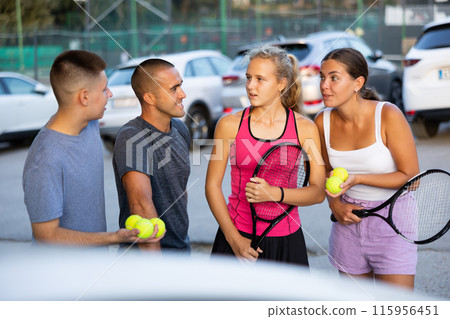 Men and women tennis players having conversation on parking lot Men and women tennis players having conversation on parking lot 115956451