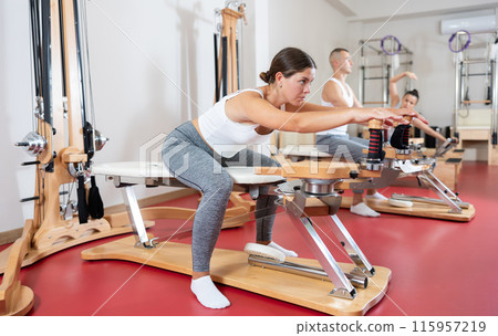 Sportive young girl training her arms turning handle of exercise machine 115957219