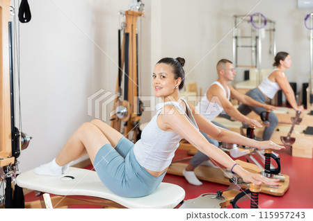 Sportive young girl training her back and shoulders on exercise machine Sportive young girl training her back and shoulders on exercise machine 115957243