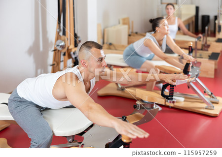 Young man stretching his arms using pilates machine 115957259