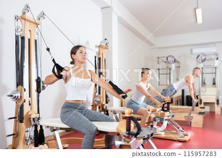 Young woman training her arms using straps Young woman training her arms using straps 115957283