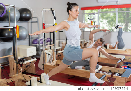 Young woman doing stretching on pilates machine 115957314