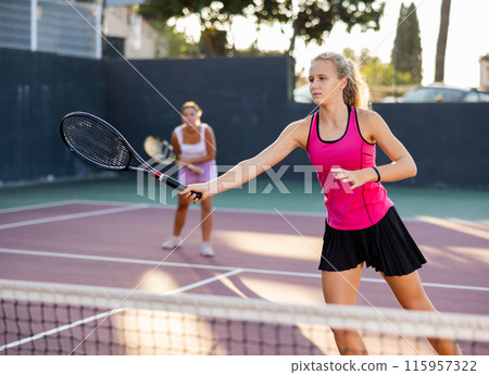Girl playing tennis match during training on court Girl playing tennis match during training on court 115957322
