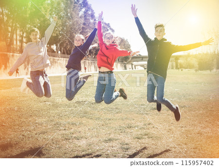 Teenagers jumping on green lawn 115957402