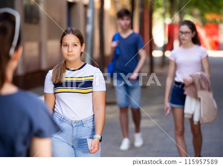 Pensive teenage girl strolling through city streets Pensive teenage girl strolling through city streets 115957589