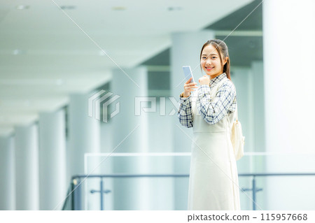 A young woman operating a smartphone 115957668
