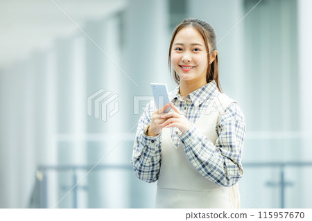 A young woman operating a smartphone 115957670