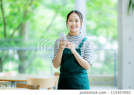 Clerk of a cafe with a smartphone Clerk of a cafe with a smartphone 115957692