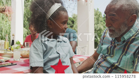 A senior biracial man and young biracial girl are sitting at a table outside A senior biracial man and young biracial girl are sitting at a table outside 115958278