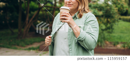Happy redhead 30s Woman holding brown paper cup of coffee on public park background, Coffee to go on the city street. Food, rest, Take away concept. 115959157