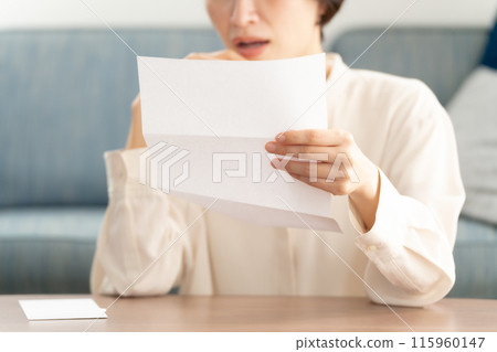 A woman crying after reading a letter 115960147