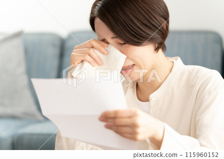 A woman crying after reading a letter A woman crying after reading a letter 115960152